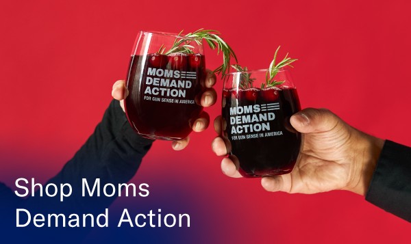 A red background with two hands holding stemless Moms Demand Action wine glasses that says 