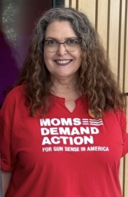 Shelley Hudson smiles while wearing a red Moms Demand Action shirt.